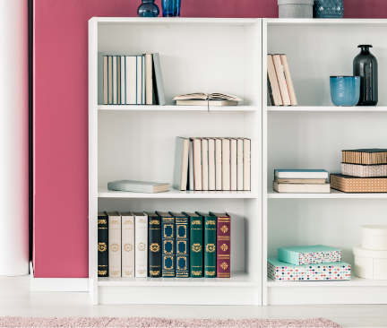 Biblioteca blanca con libros y accesorios con fondo de pared rosa