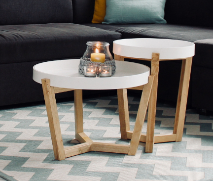 Dos mesas de centro redondas de diferentes tamaños con patas de madera y bandejas blancas